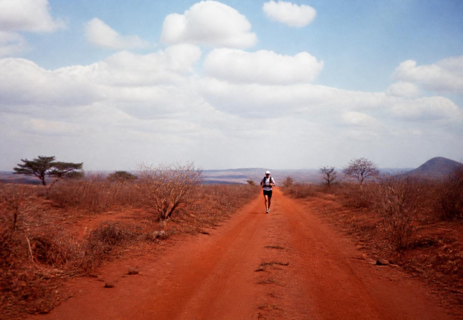 A runner on an open red dirt road outside the city